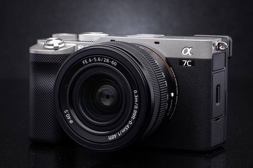 Серебристая Sony A7C с компактным зумом 28–60 мм на тёмном фоне