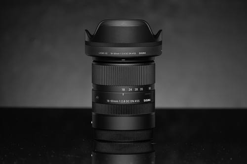 Объектив Sigma 18-50mm F2.8 DC DN Contemporary на тёмном фоне