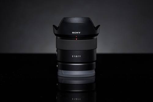 Объектив Sony E 11mm F1.8 с блендой на тёмном фоне