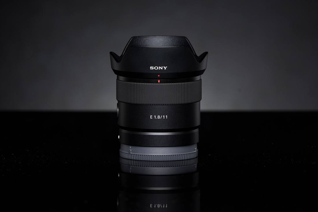 Объектив Sony E 11mm F1.8 с блендой на тёмном фоне