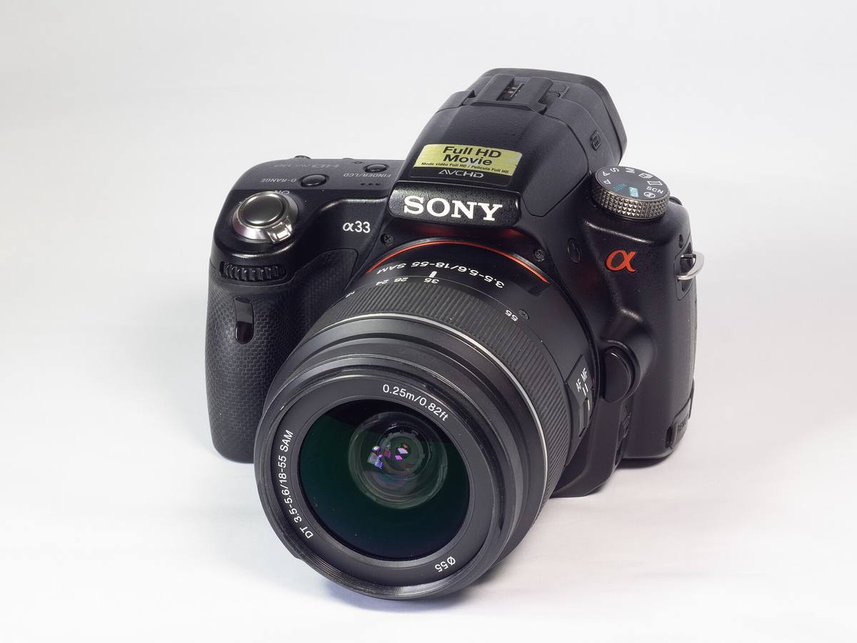 Камера Sony a33 с китовым объективом 18–55 мм на белом фоне