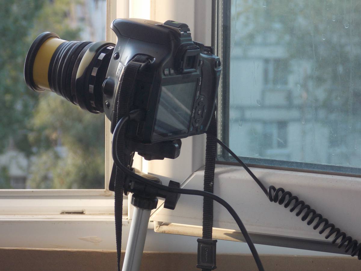 Зеркальная камера Canon на штативе у окна с советским объективом Гелиос-44 через переходник